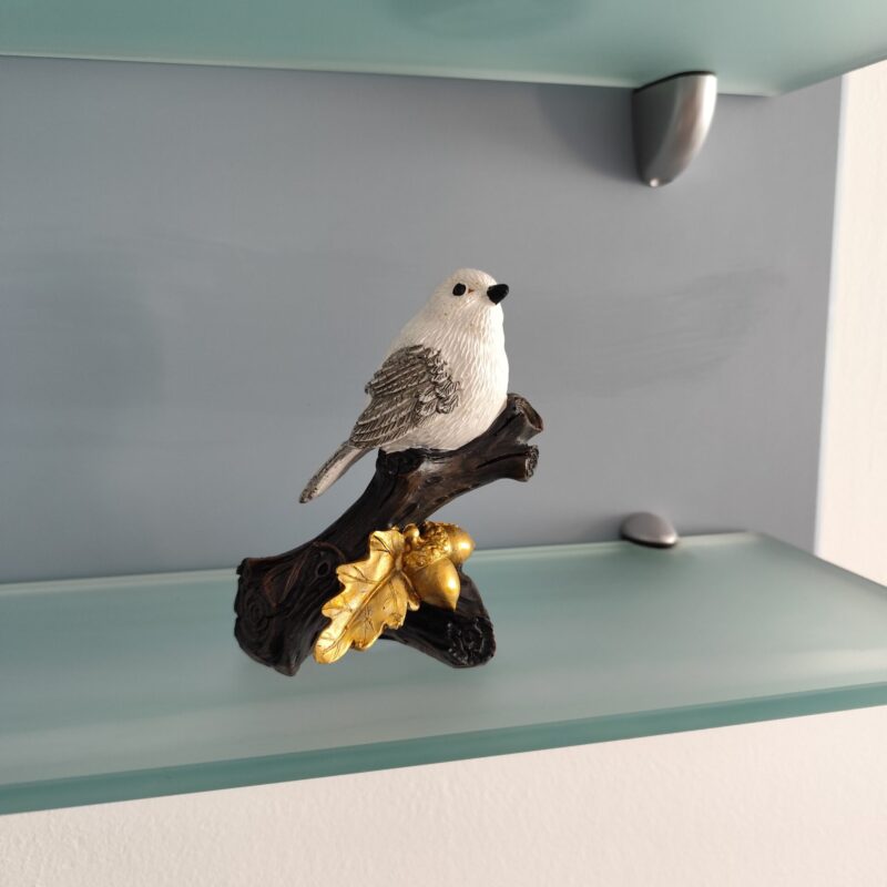 White bird resin figurine on a decorative dark branch with golden leaves and acorns