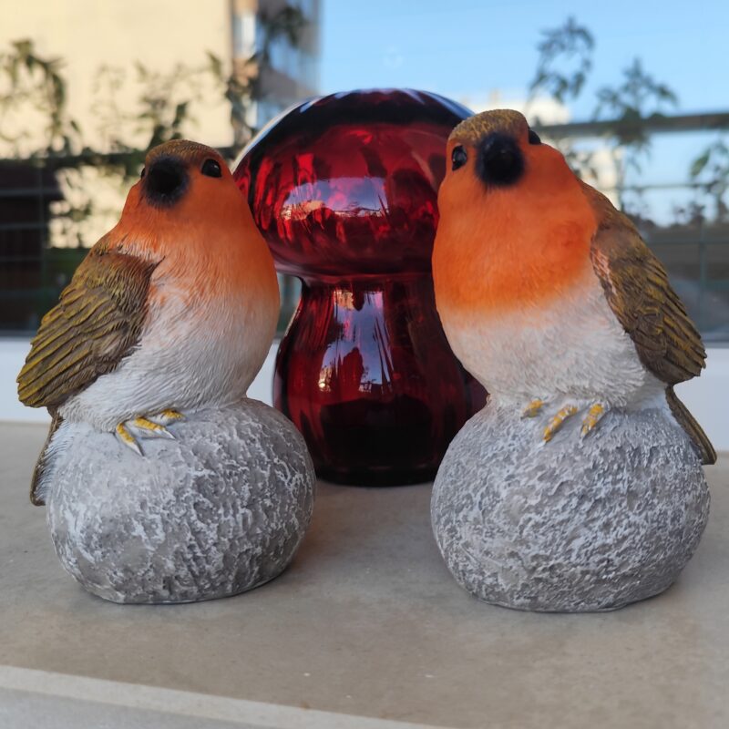 Two decorative resin bird figurines with orange breasts and textured