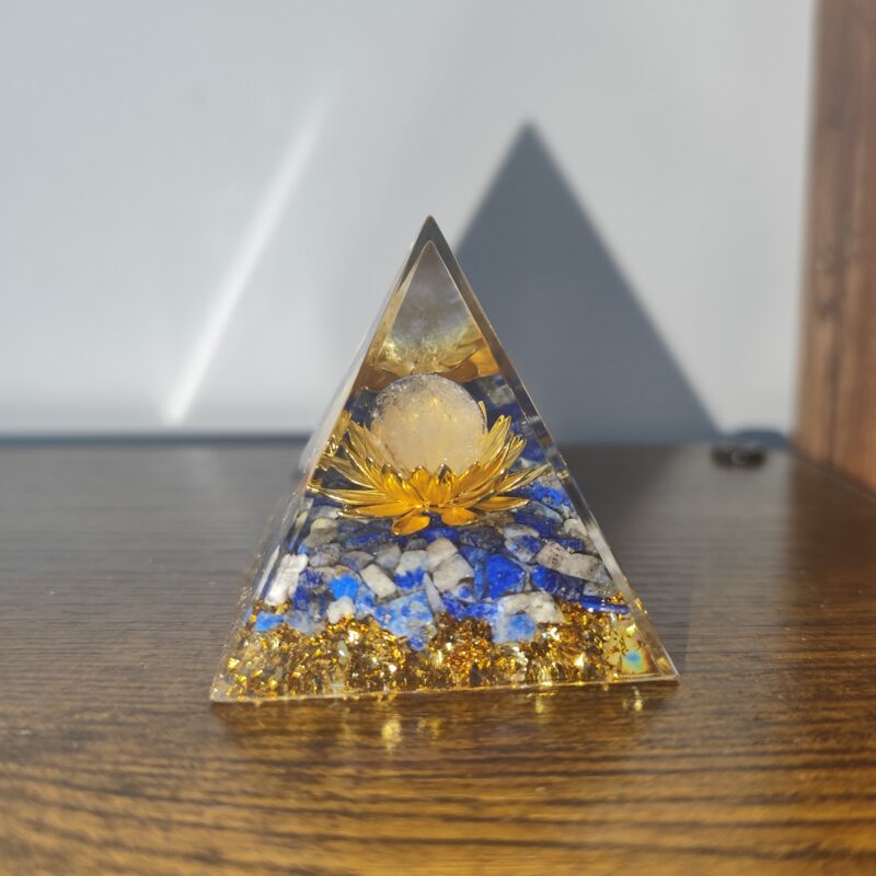 Handmade golden lotus orgonite pyramid with natural lapis lazuli stones and gold metallic details in transparent resin