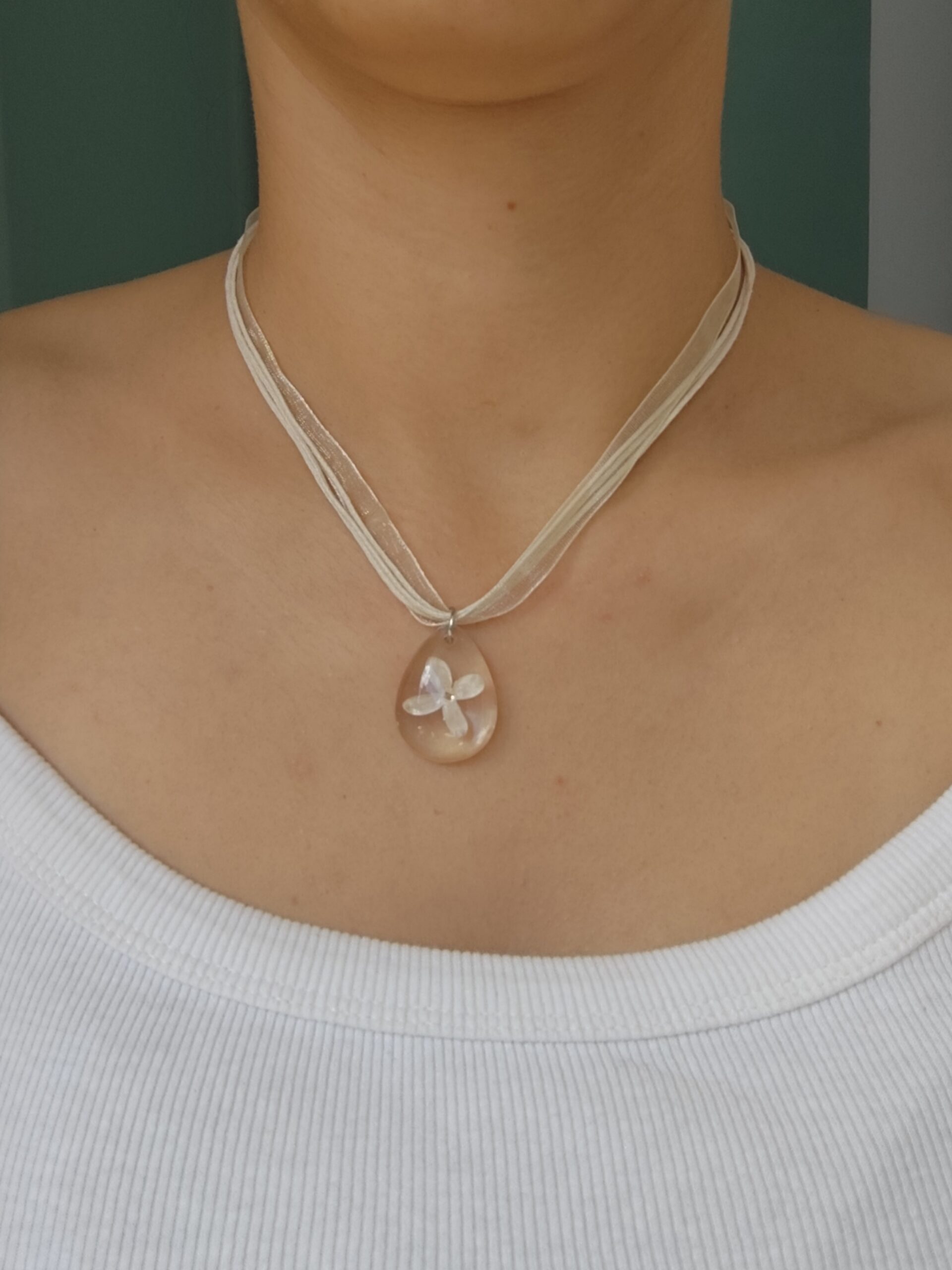 Close-up of a handmade necklace with real flowers set in a transparent resin pendant