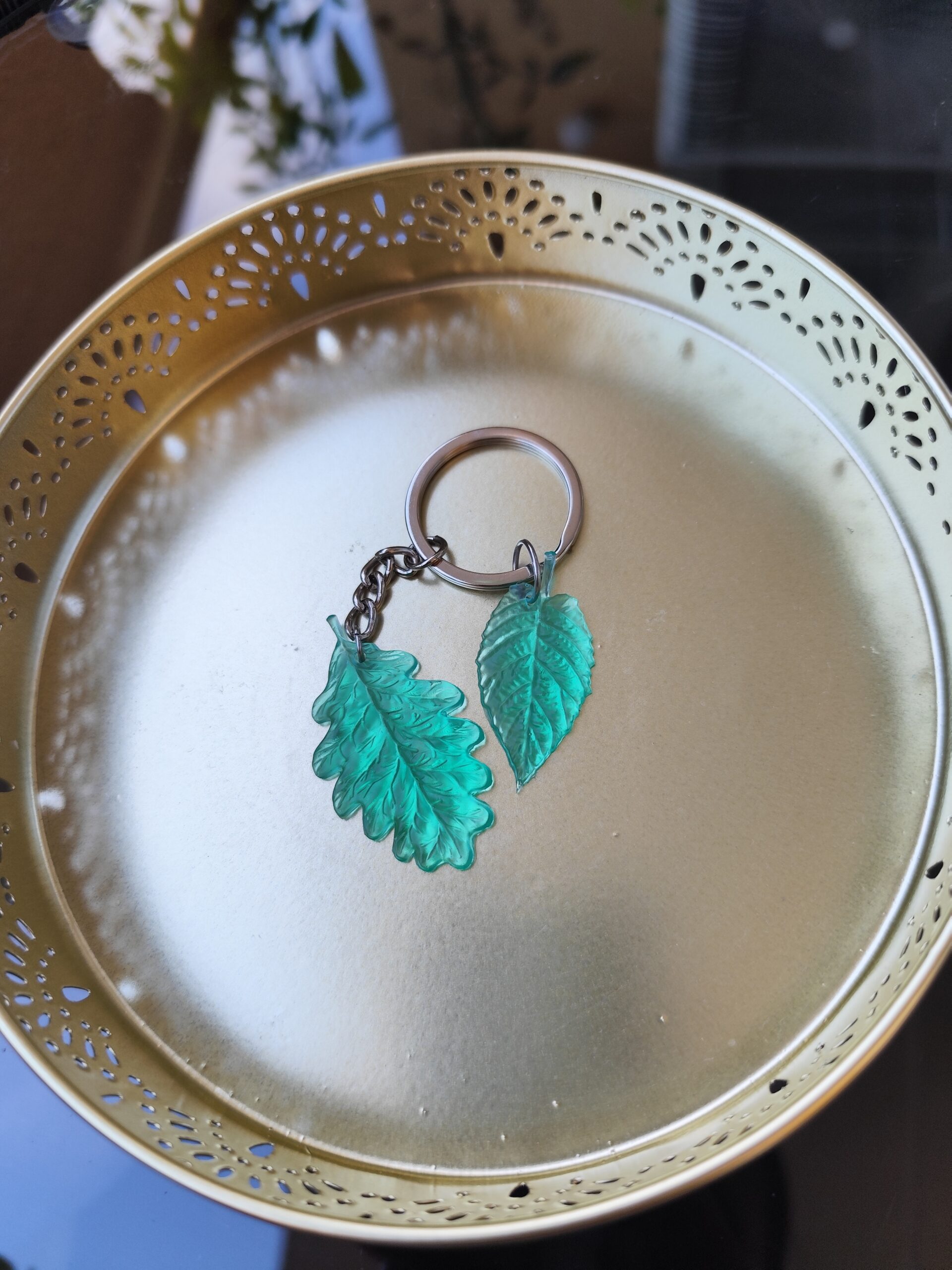 Translucent teal and green leaf epoxy resin keychain with intricate leaf details and metal chain
