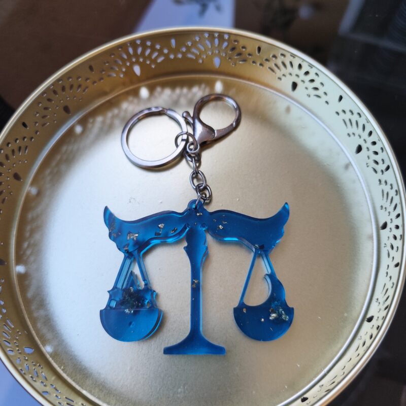 Handmade Libra zodiac scales keychain in dark blue epoxy resin with gold glitter
