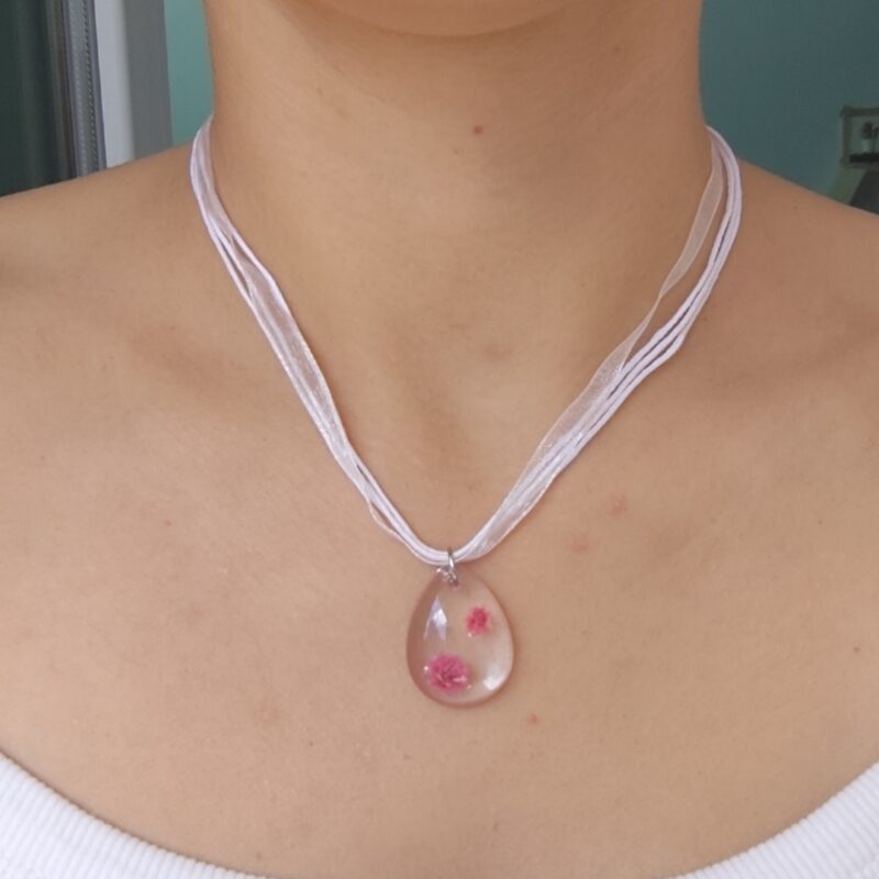 Close-up of a real flower resin pendant necklace with layered white cords