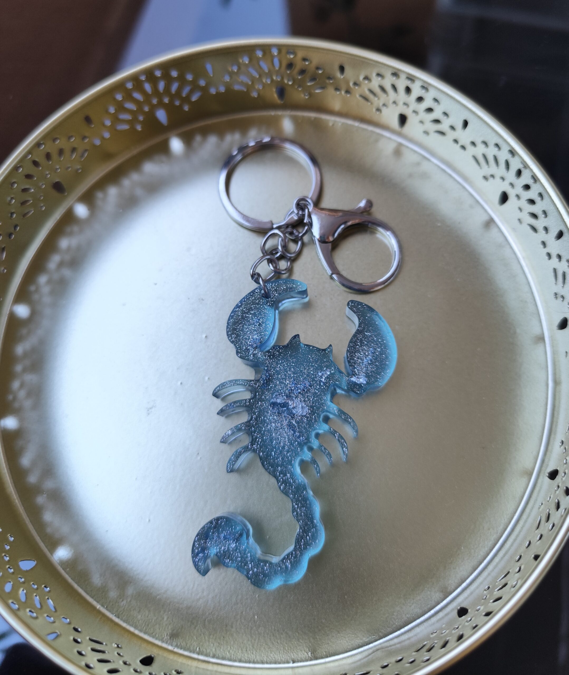 Handmade Scorpio zodiac scorpion keychain in light blue epoxy resin with silver glitter