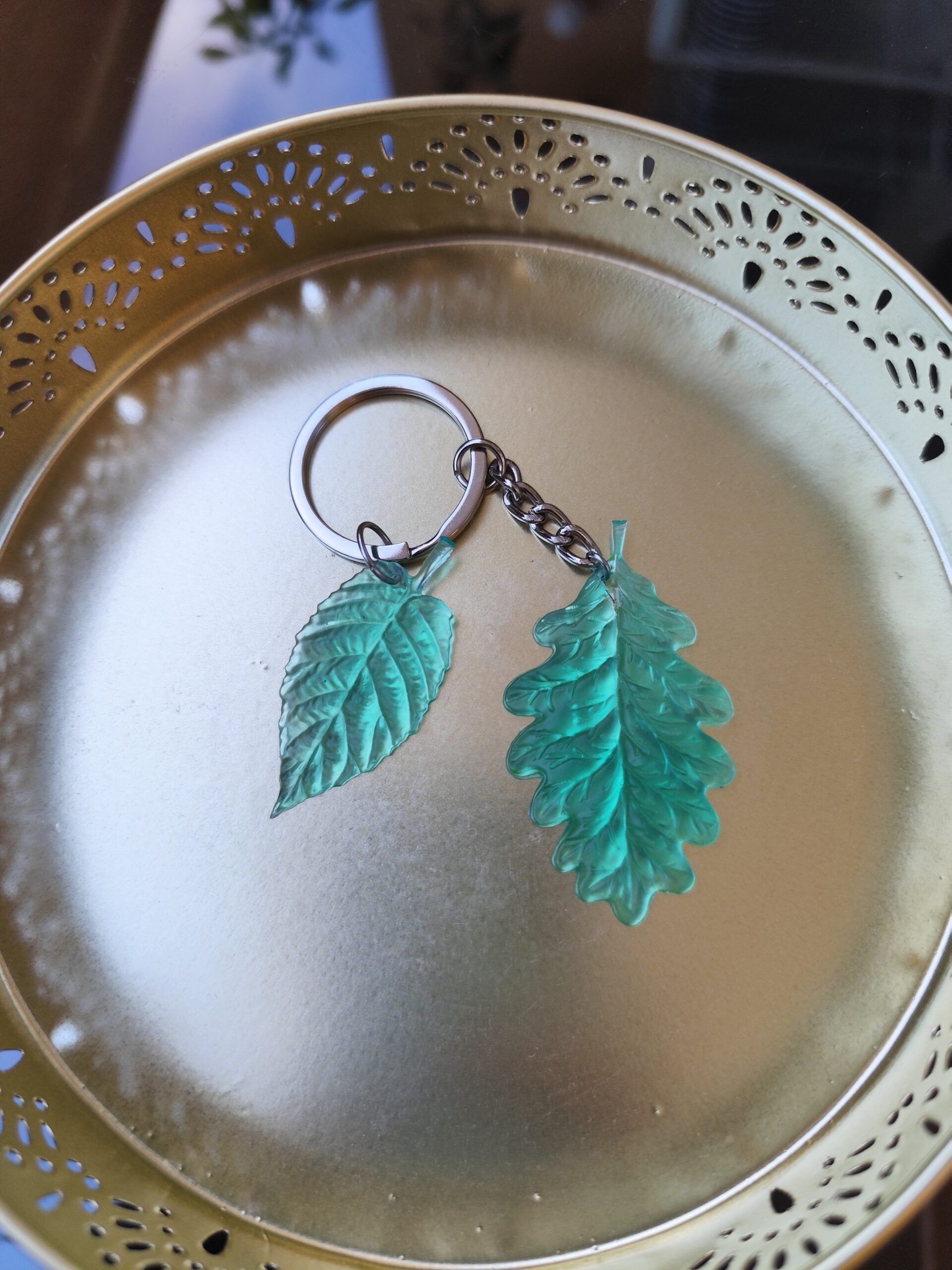 Handmade teal leaf epoxy resin keychain with detailed botanical design and silver-tone keyring
