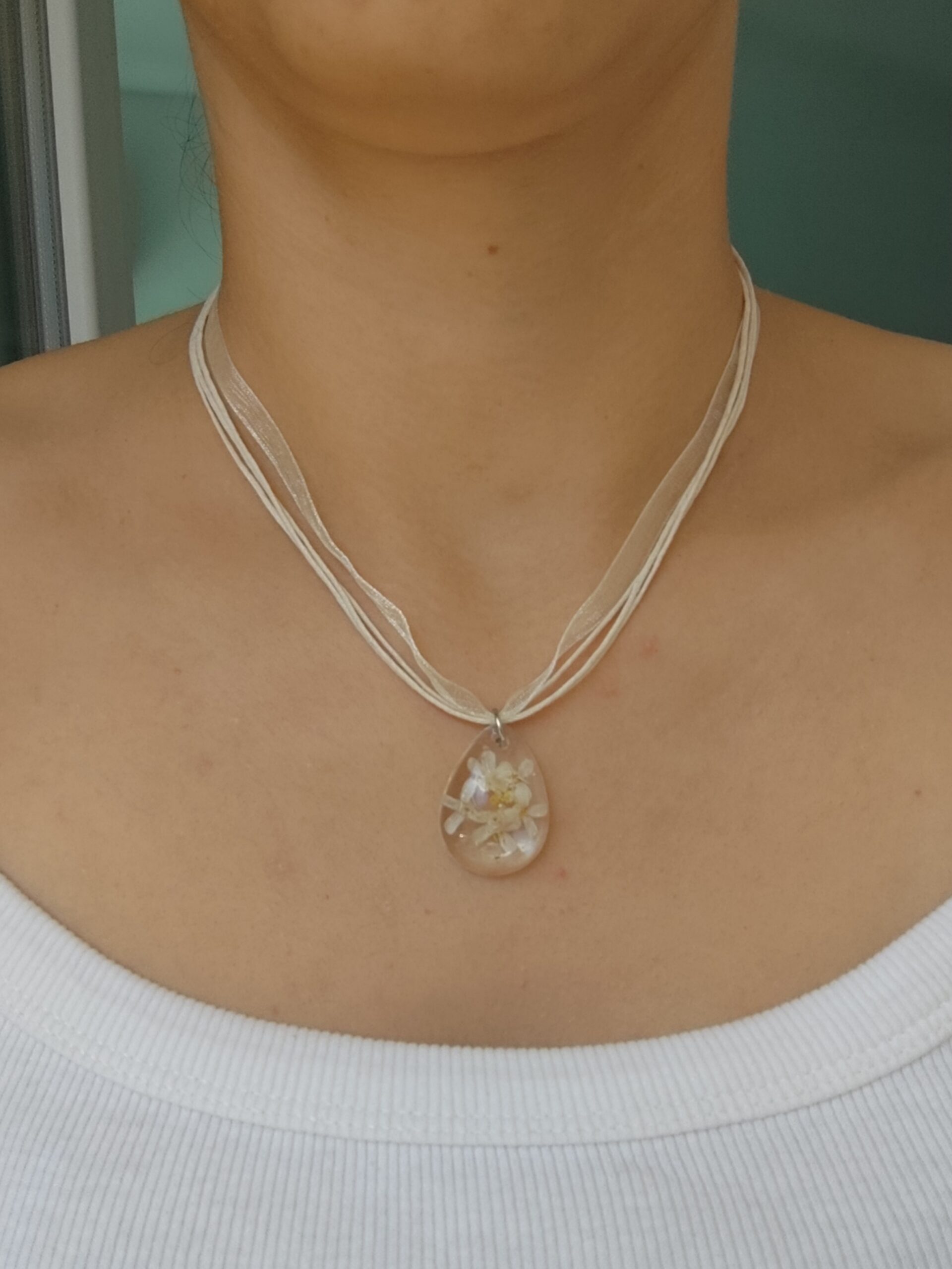 Handmade botanical necklace featuring real flowers inside a clear epoxy resin pendant